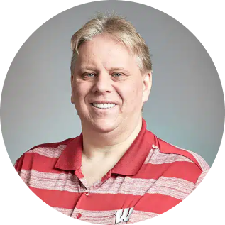 A man with blond hair, wearing a new red and white striped polo shirt with a "W" logo, smiles warmly at the camera.